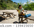 Woman Packing Yoga Mat and Exercise Gear Into Backpack at Outdoor Picnic Table 139415650
