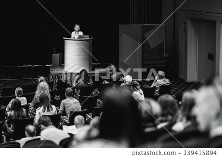 Female speaker giving a talk on corporate business conference. Unrecognizable people in audience at conference hall. Business and Entrepreneurship event Female speaker giving a talk on corporate business conference. Unrecognizable people in audience at conference hall. Business and Entrepreneurship event 139415894
