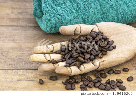 Articulated Wooden Hand Holding Fresh Roasted Coffee Beans Used to Exfoliate Skin in Natural Spa Beauty Treatment on Rustic Wood Articulated Wooden Hand Holding Fresh Roasted Coffee Beans Used to Exfoliate Skin in Natural Spa Beauty Treatment on Rustic Wood 139416265