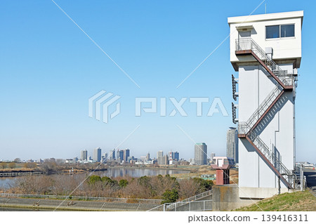 The Shibakawa floodgate stands tall against the blue sky, offering a refreshing view of modern urban infrastructure and the distant cityscape. The Shibakawa floodgate stands tall against the blue sky, offering a refreshing view of modern urban infrastructure and the distant cityscape. 139416311