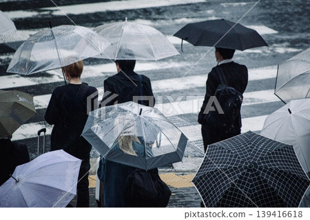 雨季景象:下雨天,人們撐著傘在紅綠燈前等候。 雨季景象:下雨天,人們撐著傘在紅綠燈前等候。 139416618