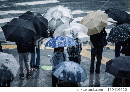 Image of the rainy season: people waiting at a traffic light with umbrellas on a rainy day. 139416620