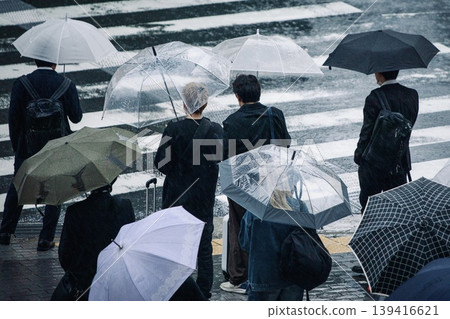 雨季景象:下雨天,人們撐著傘在紅綠燈前等候。 雨季景象:下雨天,人們撐著傘在紅綠燈前等候。 139416621