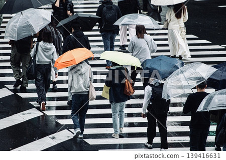People crossing the street with umbrellas on a rainy day People crossing the street with umbrellas on a rainy day 139416631