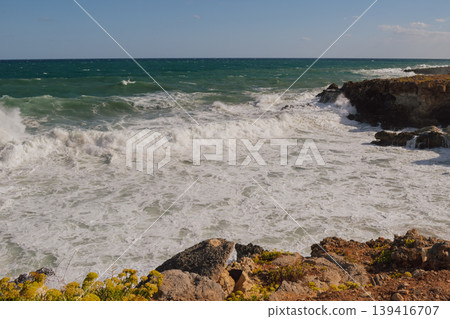 Powerful surf hitting rocks emerald blue sea white foam and clear sky. 139416707