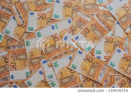 Dense array of 50 Euro bills in an artistic scatter. High-detail macro of orange European currency featuring Renaissance architecture, holograms, and watermarks Dense array of 50 Euro bills in an artistic scatter. High-detail macro of orange European currency featuring Renaissance architecture, holograms, and watermarks 139416724