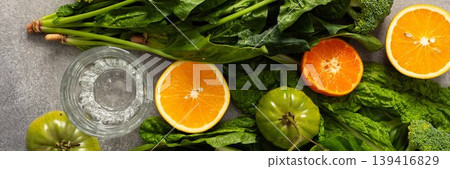 Fresh spinach, chard, and broccoli sit among sliced oranges and tangerines as juice is prepared in a kitchen. The scene captures a vibrant approach to healthy drinking, banner Fresh spinach, chard, and broccoli sit among sliced oranges and tangerines as juice is prepared in a kitchen. The scene captures a vibrant approach to healthy drinking, banner 139416829