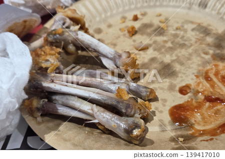 Leftover Chicken Bones and Sauce on Paper Plate Leftover Chicken Bones and Sauce on Paper Plate 139417010