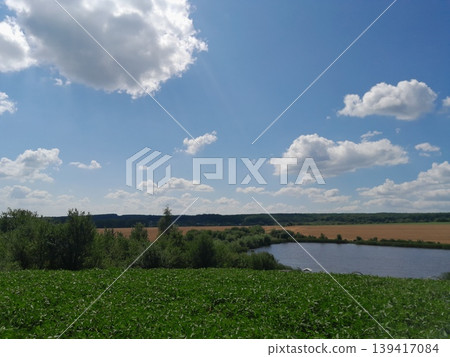 Fluffy white clouds over landscape on a sunny day Fluffy white clouds over landscape on a sunny day 139417084