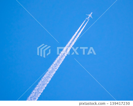 Airplane flying high in the sky leaving white trails during clear day with blue background Airplane flying high in the sky leaving white trails during clear day with blue background 139417230