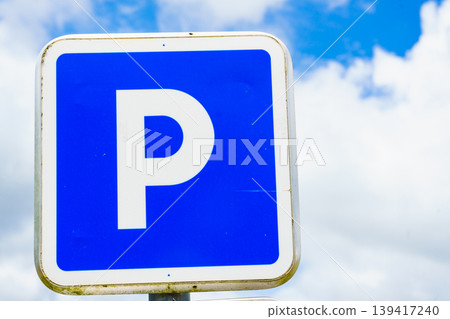 Parking sign under blue sky with fluffy clouds indicating available parking space in a public area Parking sign under blue sky with fluffy clouds indicating available parking space in a public area 139417240
