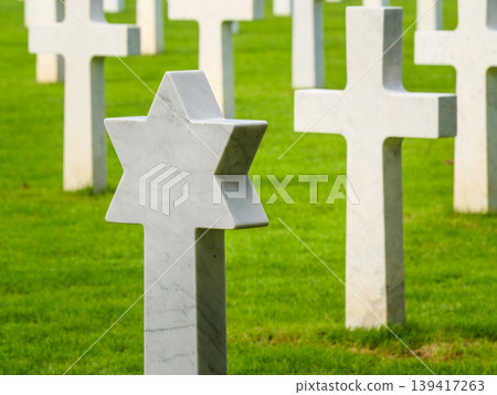 Gravestones stand in a cemetery with a star of David among crosses in the grassy field Gravestones stand in a cemetery with a star of David among crosses in the grassy field 139417263