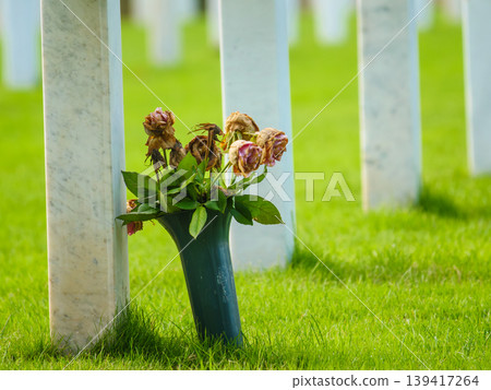 Crosses stand in a row as flowers sit at a grave in a cemetery where people remember their loved ones Crosses stand in a row as flowers sit at a grave in a cemetery where people remember their loved ones 139417264