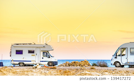 Warm sunset view at the beach with a two campers parked along the shore Warm sunset view at the beach with a two campers parked along the shore 139417272
