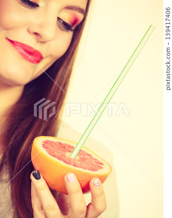 Woman holds grapefruit drinking juice from fruit Woman holds grapefruit drinking juice from fruit 139417406