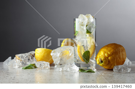 Tall glass with lemon wedges, ice cubes and mint leaves. Tall glass with lemon wedges, ice cubes and mint leaves. 139417460