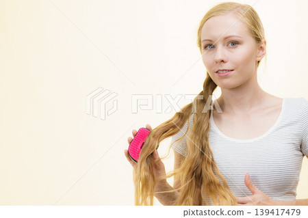 Blonde girl brushing her long hair Blonde girl brushing her long hair 139417479