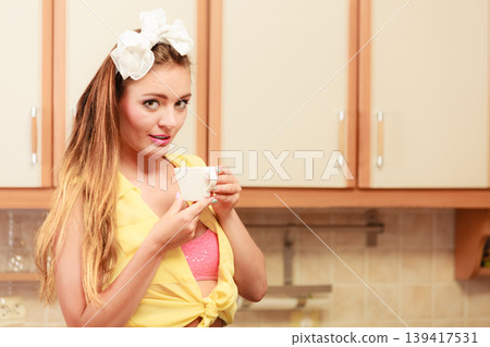 Pretty pin up girl drinking tea or coffee at home. Pretty pin up girl drinking tea or coffee at home. 139417531