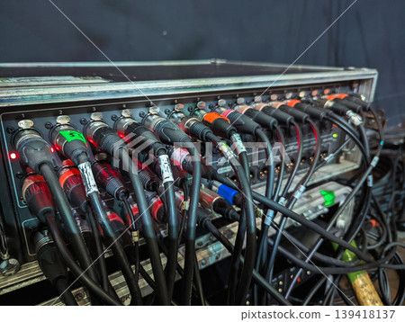 A complex array of colorful cables intricately connected to a professional audio mixer in a recording studio. A complex array of colorful cables intricately connected to a professional audio mixer in a recording studio. 139418137