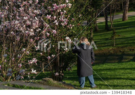 Woman standing near blooming tree in Emirgan Park in Istanbul, spring flowers, green grass and sunlight in natural outdoor setting. Family leisure, urban nature, outdoor recreation, travel content Woman standing near blooming tree in Emirgan Park in Istanbul, spring flowers, green grass and sunlight in natural outdoor setting. Family leisure, urban nature, outdoor recreation, travel content 139418348