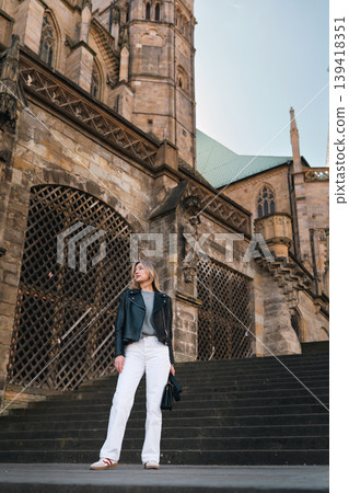 Stylish Woman Standing on Stone Steps Near Historic Gothic Cathedral Stylish Woman Standing on Stone Steps Near Historic Gothic Cathedral 139418351