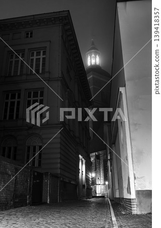 Illuminated Tower Between Narrow Streets at Night in Black and White Illuminated Tower Between Narrow Streets at Night in Black and White 139418357