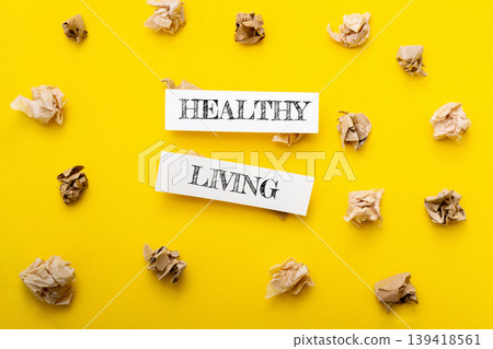Healthy living concept with crumpled paper surrounding bold text on vibrant yellow background, symbolizing wellness and lifestyle choices for improved health and vitality 139418561