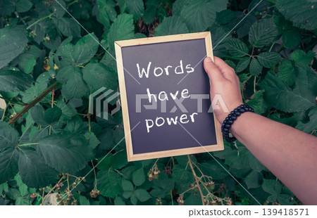 Hand holding a chalkboard sign with inspirational quote surrounded by lush green foliage Hand holding a chalkboard sign with inspirational quote surrounded by lush green foliage 139418571