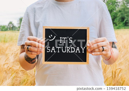Person holding a chalkboard with the words Its Saturday written on it Person holding a chalkboard with the words Its Saturday written on it 139418752