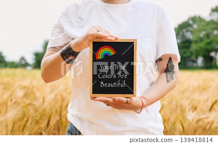 Woman holds a rainbow and a sign that says Your true colors are beautiful. Woman holds a rainbow and a sign that says Your true colors are beautiful. 139418814