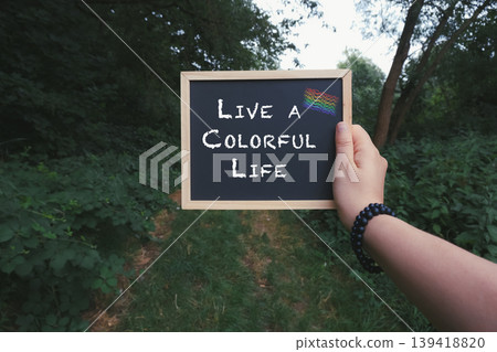 Person holding a chalkboard with the words Live a colorful life Person holding a chalkboard with the words Live a colorful life 139418820