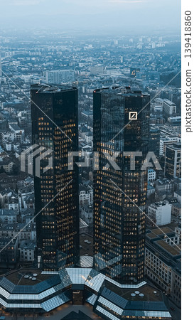 Modern skyscrapers with reflective glass facades towering over urban landscape at dusk Modern skyscrapers with reflective glass facades towering over urban landscape at dusk 139418860