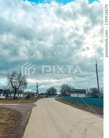 Scenic rural road winding through countryside with dramatic cloud formations overhead, showcasing the beauty of nature and tranquility in rural life Scenic rural road winding through countryside with dramatic cloud formations overhead, showcasing the beauty of nature and tranquility in rural life 139418879