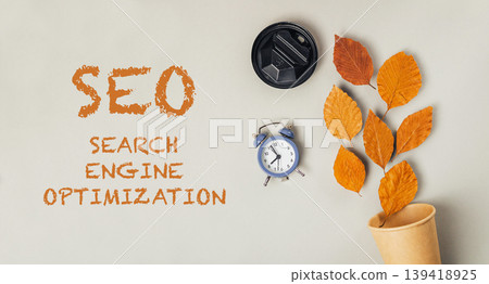 SEO concept with autumn leaves, clock, and coffee cup on a neutral background for digital marketing SEO concept with autumn leaves, clock, and coffee cup on a neutral background for digital marketing 139418925