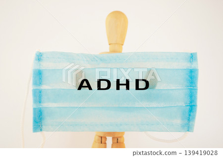 Wooden mannequin wearing a blue mask with the letters ADHD displayed prominently in front Wooden mannequin wearing a blue mask with the letters ADHD displayed prominently in front 139419028