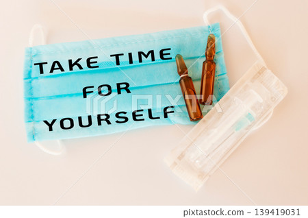 Blue medical mask with motivational text and ampoules on a clean surface for wellness concept Blue medical mask with motivational text and ampoules on a clean surface for wellness concept 139419031