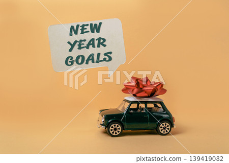 Miniature car with red bow and speech bubble showcasing New Year goals and festive spirit 139419082