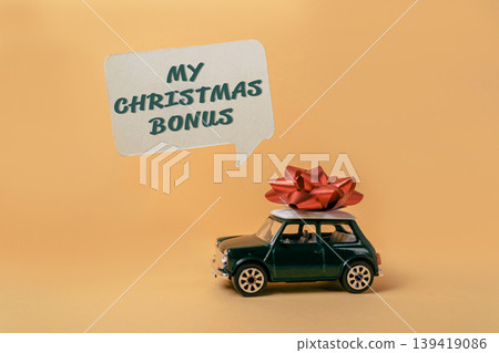 Toy car with red bow on top and speech bubble displaying festive message for holiday season Toy car with red bow on top and speech bubble displaying festive message for holiday season 139419086