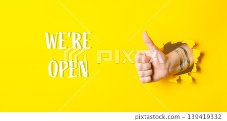 hand on yellow background with thumb up with inscription Were open hand on yellow background with thumb up with inscription Were open 139419332