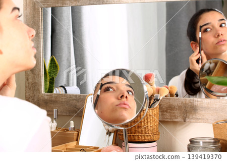 Teen Girl Applying Makeup in Front of Mirror 139419370