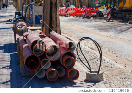 Stack of large drainage pipes on sidewalk during urban road construction and utility installation Stack of large drainage pipes on sidewalk during urban road construction and utility installation 139419626