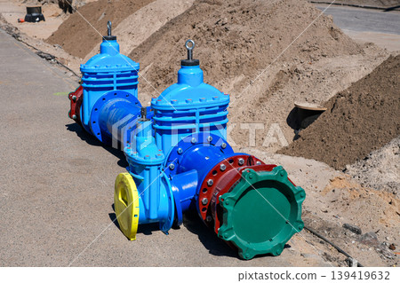 Large industrial pipeline valves on roadside construction site with sand piles and utility works 139419632