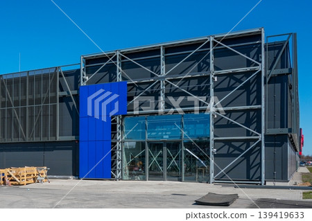 Modern industrial building facade with glass entrance steel frame and construction equipment Modern industrial building facade with glass entrance steel frame and construction equipment 139419633