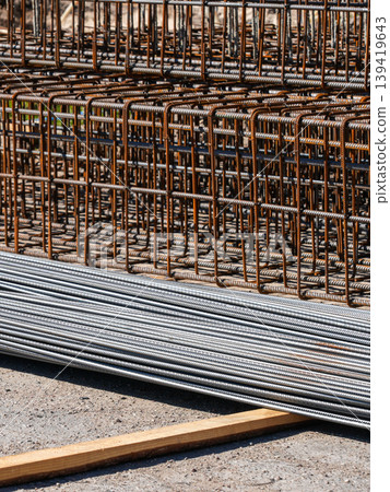 Stacked steel reinforcement bars and welded rebar cages at construction site ready for building work Stacked steel reinforcement bars and welded rebar cages at construction site ready for building work 139419643