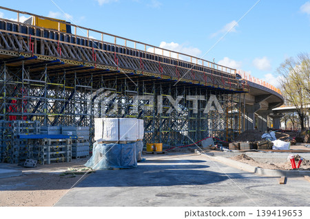 Elevated road bridge under construction with dense scaffolding and formwork on a sunny day scene 139419653