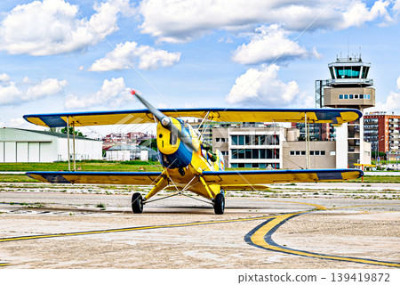 A yellow single-engine ultralight aircraft on the airfield runway. 139419872
