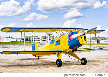 A yellow single-engine ultralight aircraft on the airfield runway. 139419874