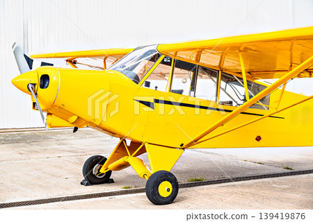 A yellow single-engine ultralight aircraft on the airfield runway. 139419876