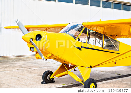 A yellow single-engine ultralight aircraft on the airfield runway. 139419877