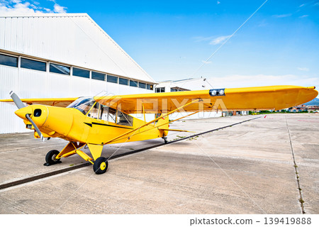 A yellow single-engine ultralight aircraft on the airfield runway. A yellow single-engine ultralight aircraft on the airfield runway. 139419888